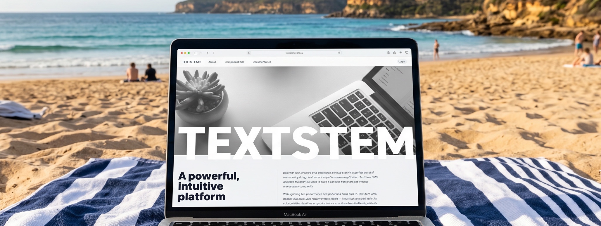 A laptop displaying a website named "TEXTSTEM" is placed on a beach towel on a sandy beach, with the ocean and rocks in the background. Beachgoers can be seen enjoying the sun and water in the distance.